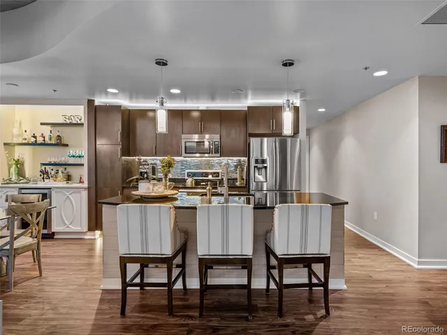 a kitchen with kitchen island a dining table chairs stainless steel appliances and cabinets