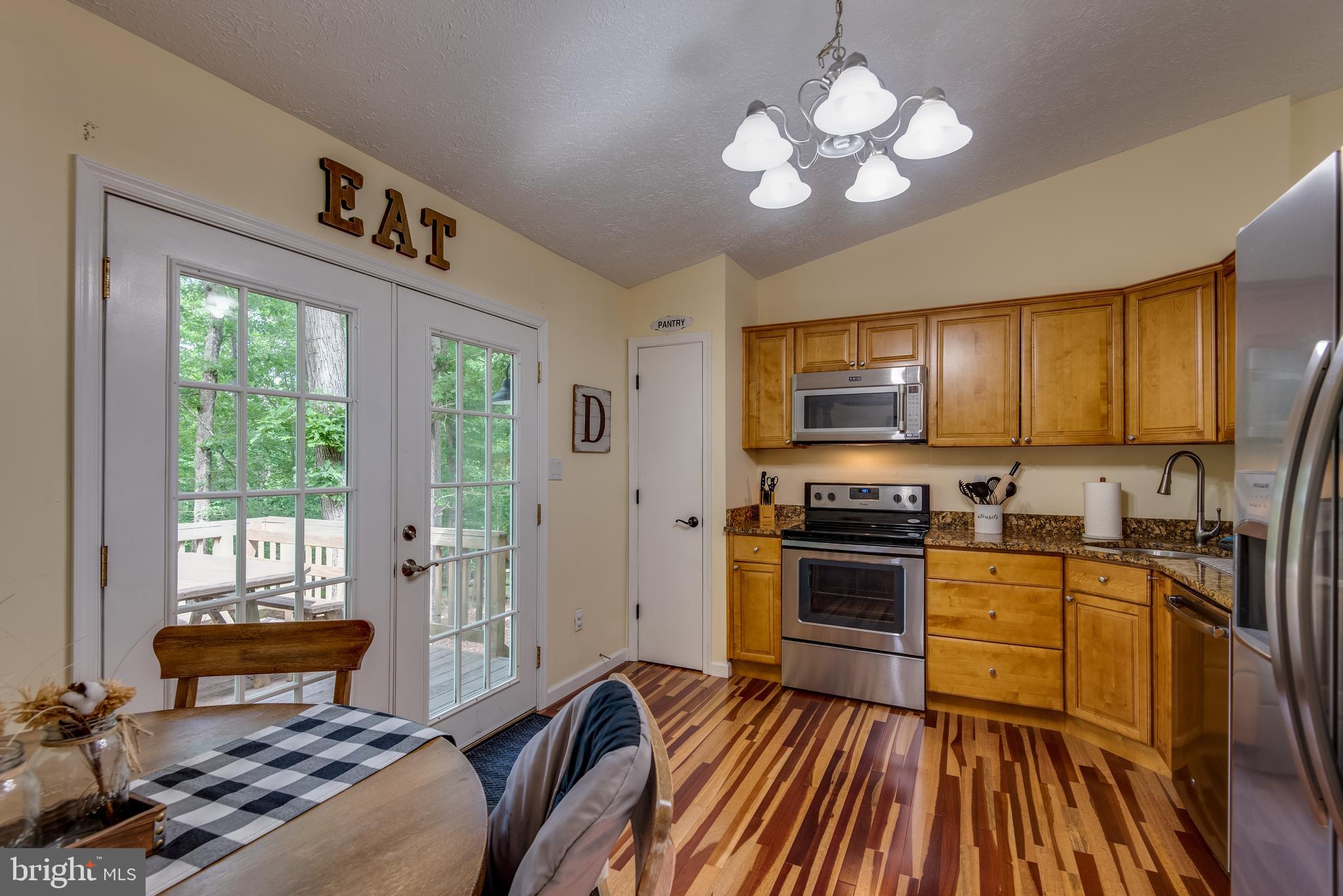 12430 Ridge Road Lusby, MD 20657 - Photo 3 of 36 a kitchen with stainless steel appliances granite countertop a stove top oven a sink dishwasher a dining table and chairs with wooden floor