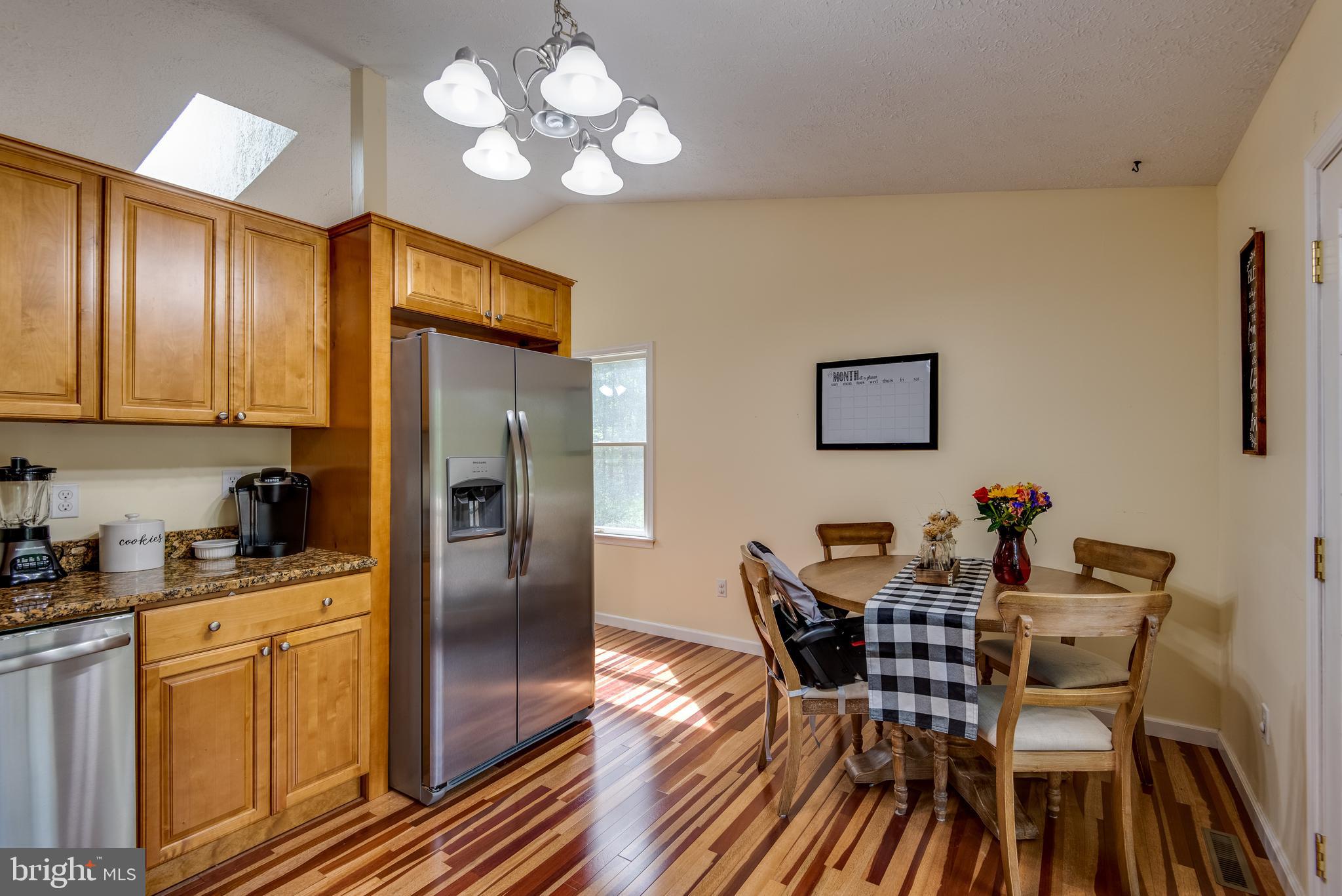 12430 Ridge Road Lusby, MD 20657 - Photo 4 of 36 a dining room with wooden floor a chandelier a wooden table and chairs