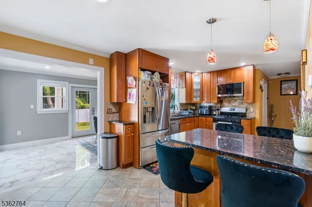 a kitchen with stainless steel appliances granite countertop a refrigerator a stove and a sink