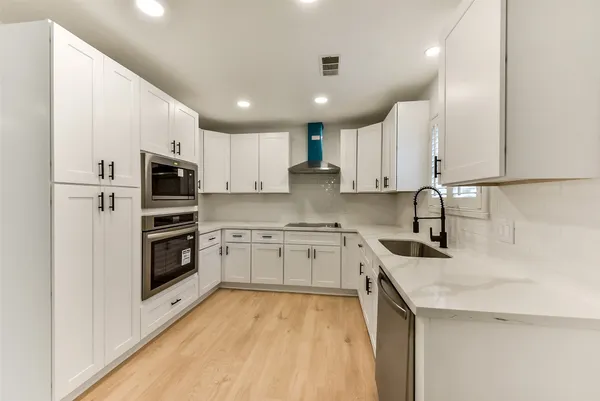 a kitchen with granite countertop a sink a counter top space stainless steel appliances and cabinets