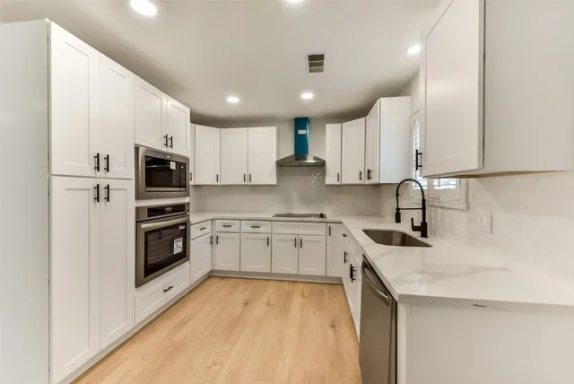 a kitchen with granite countertop a sink a counter top space stainless steel appliances and cabinets