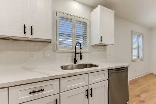 a kitchen with granite countertop white cabinets and sink