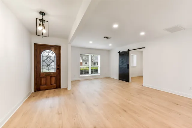a view of an empty room with a window and wooden floor