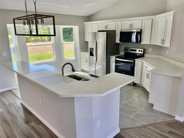 a kitchen with stainless steel appliances a sink a stove a refrigerator a window