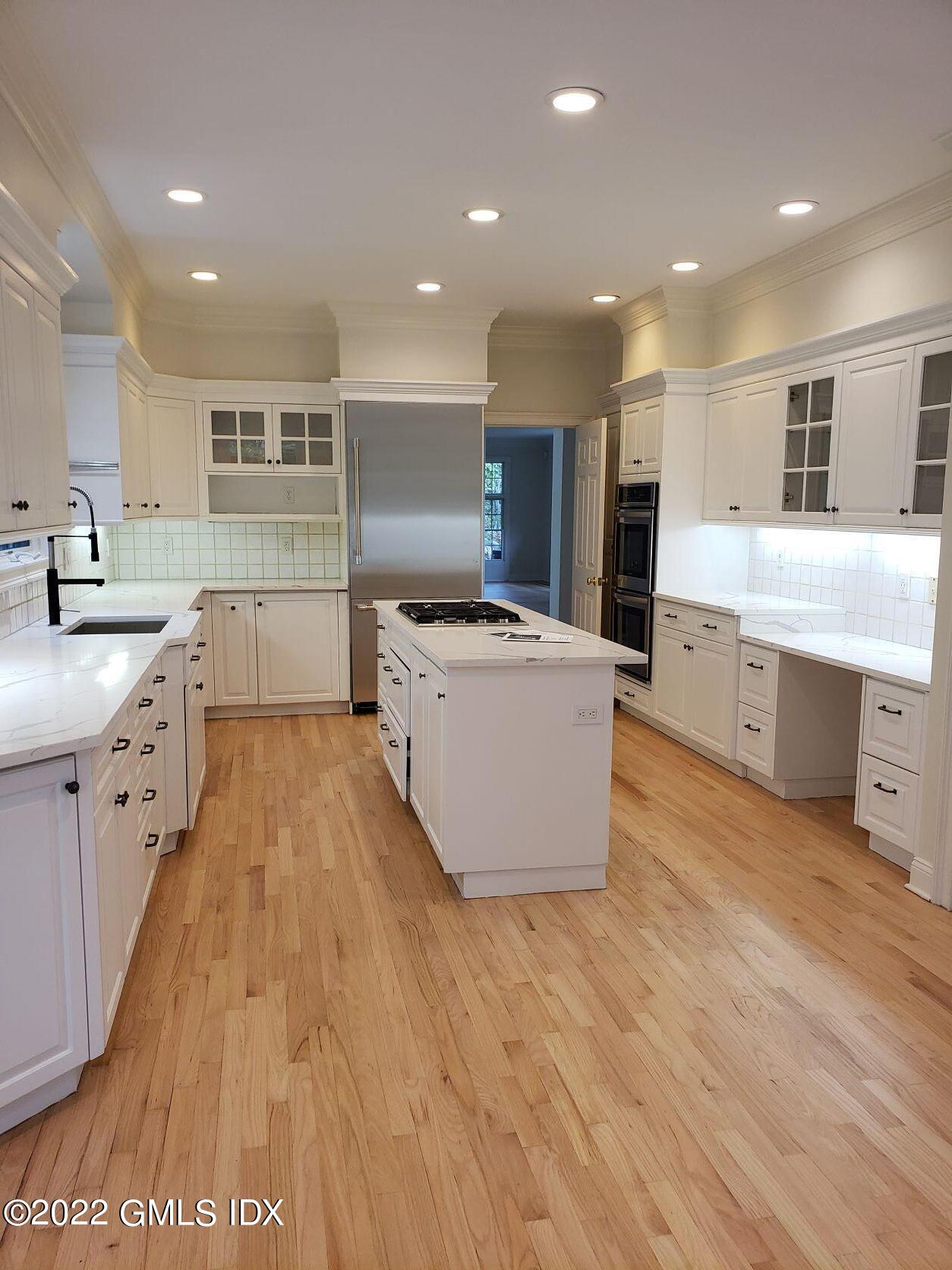 15 Horseshoe Road Cos Cob, CT 06807 - Photo 9 of 33 a large kitchen with stainless steel appliances a stove a sink a refrigerator and white cabinets with wooden floor
