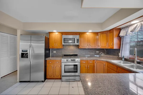 a kitchen with stainless steel appliances granite countertop a sink a stove and a refrigerator