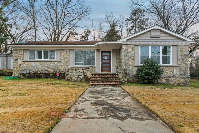 a front view of a house with a yard outdoor seating and covered with trees