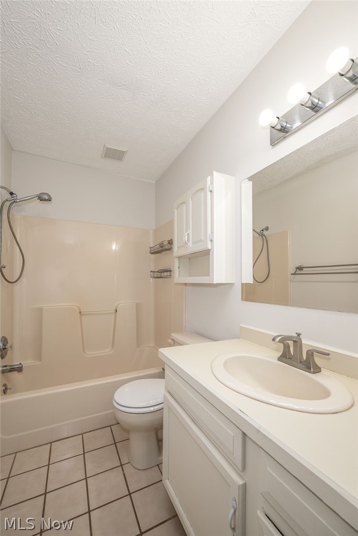 5203 Cline Road Kent, OH 44240 - Photo 9 of 35 Vanity with undermount sink and brushed nickel faucet, tiled flooring, white built-in cabinetry, and integrated shower/tub combination