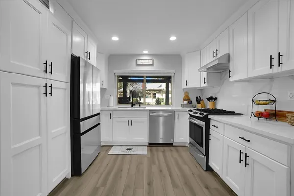 a kitchen with white cabinets and stainless steel appliances