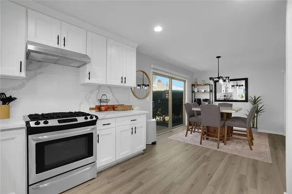 a kitchen with granite countertop a stove a sink dishwasher and a stove with wooden floor