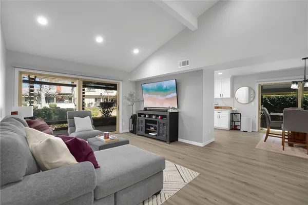 a living room with furniture large window and wooden floor