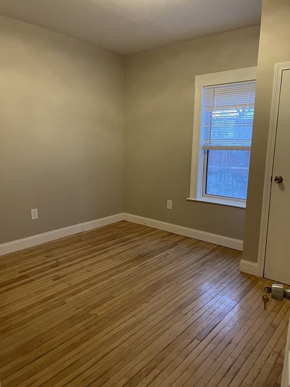 52 Houghton Street, Unit 1 Worcester, MA 01604 - Photo 13 of 15 a view of an empty room with wooden floor and a window