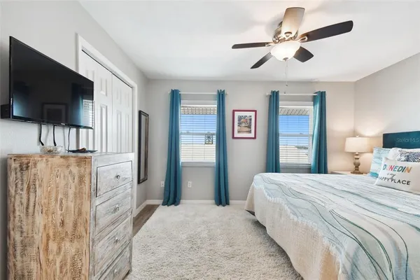 a bedroom with a bed flat screen tv and a ceiling fan