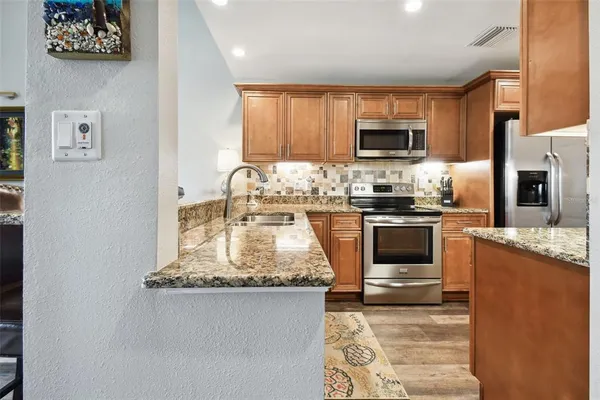 a kitchen with stainless steel appliances granite countertop a stove top oven a sink a counter space and cabinets