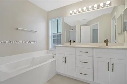 a bathroom with a bathtub a double vanity sink and a mirror