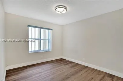 an empty room with wooden floor cabinet and windows