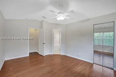 an empty room with wooden floor chandelier fan and windows
