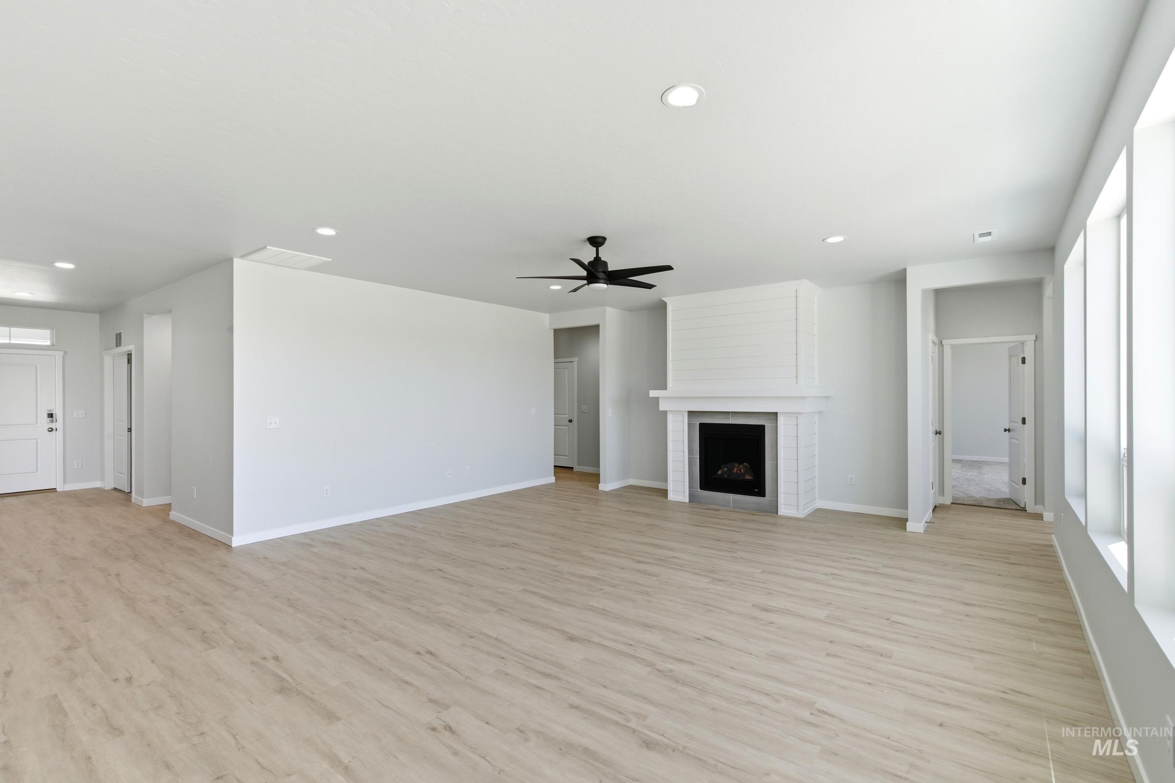 13663 Redway Court Caldwell, ID 83607 - Photo 12 of 32 Spacious interior featuring light wood-finish flooring, a contemporary fireplace with a shiplap surround, multiple windows, recessed lighting, and a ceiling fan