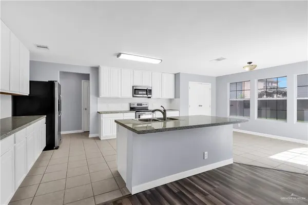 a kitchen with white cabinets and sink