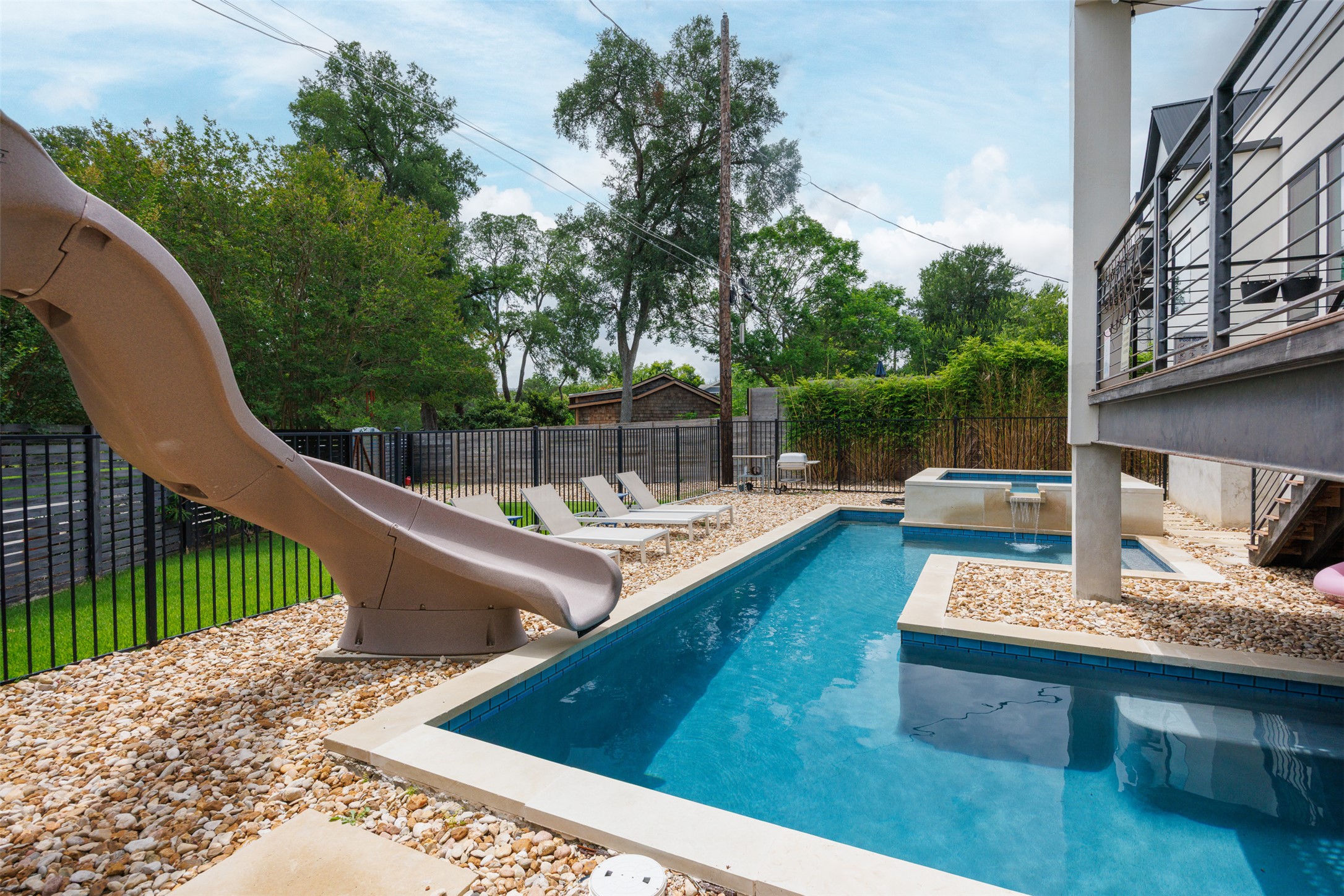 4103 Ridgelea Drive Austin, TX 78731 - Photo 2 of 26 An inviting backyard oasis features a glistening pool with a slide and a bubbling spa, perfect for relaxation.