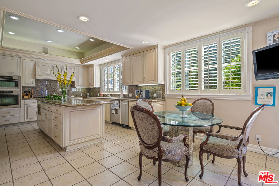 511 North Canon Drive Beverly Hills, CA 90210 - Photo 12 of 34 a kitchen with stainless steel appliances granite countertop a stove a sink a microwave a dining table and chairs
