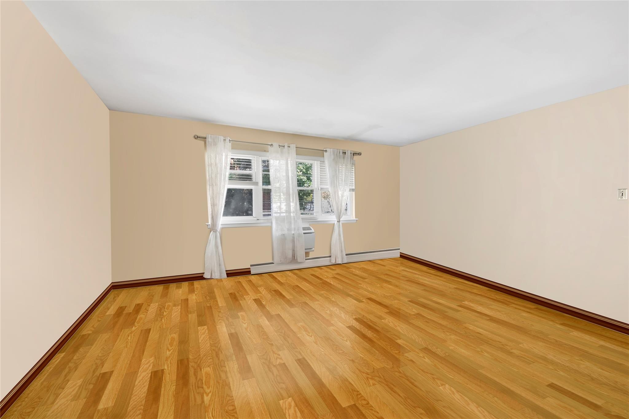 Spare room featuring light wood finished floors, a baseboard radiator, and baseboards