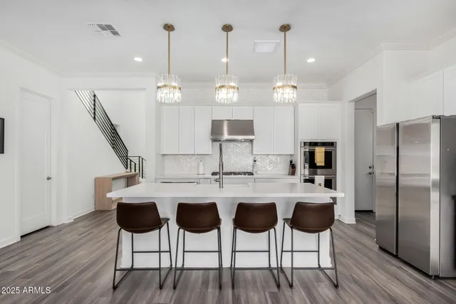 a kitchen with a dining table chairs and wooden floor