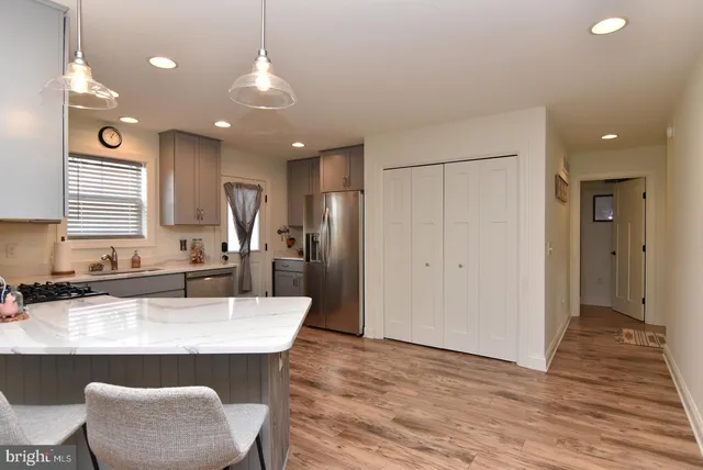 a kitchen with granite countertop a refrigerator a sink dishwasher a dining table and chairs with wooden floor