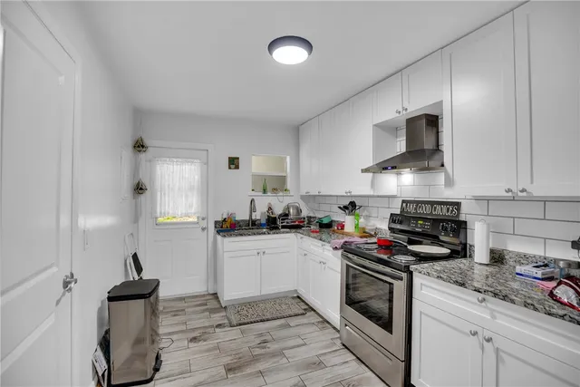 a kitchen with stainless steel appliances granite countertop a stove top oven a sink dishwasher and white cabinets
