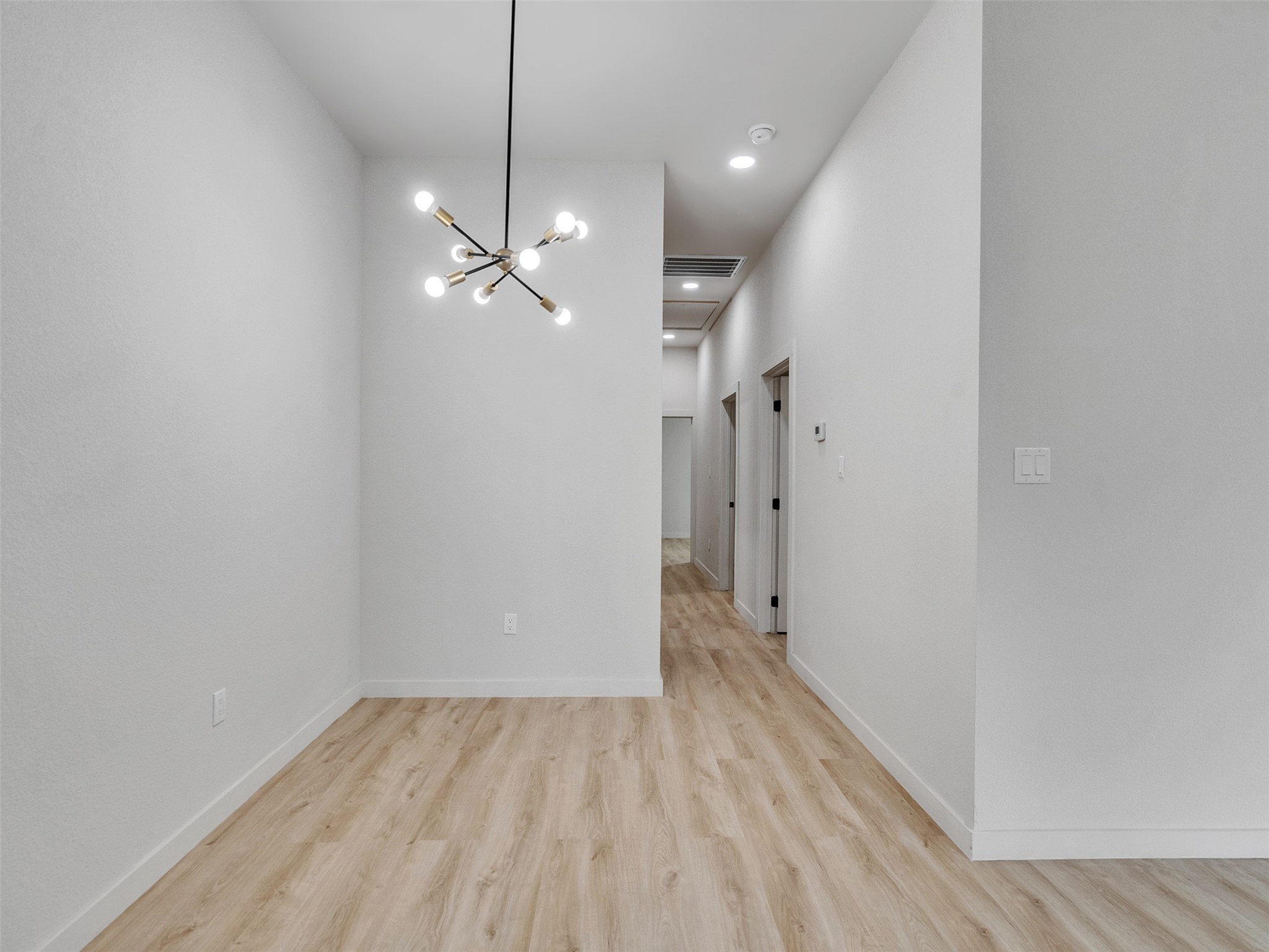 9707 Cargill Street, Unit AB Houston, TX 77029 - Photo 18 of 32 a view of a hallway with a chandelier fan and wooden floor