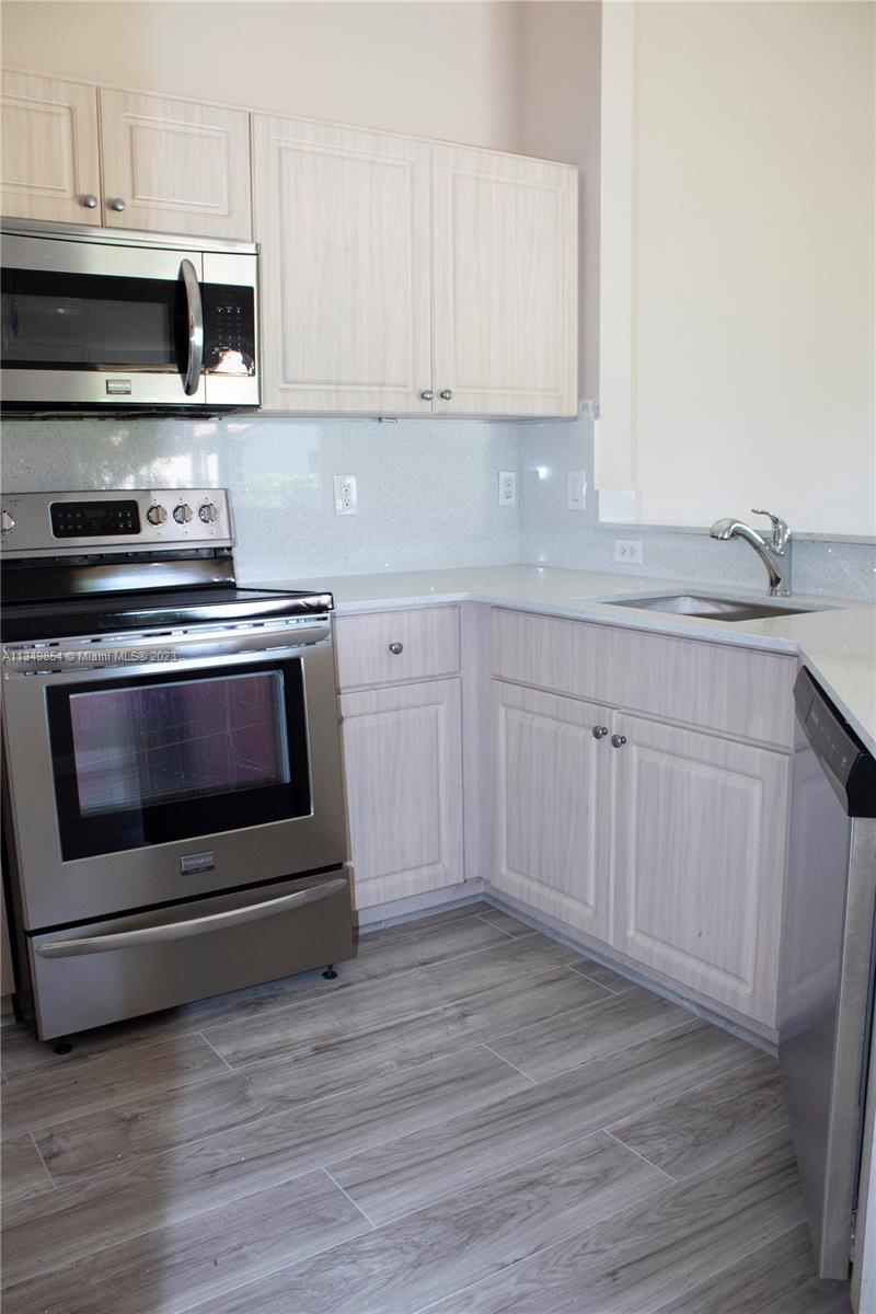 13221 Southwest 53rd Street Miramar, FL 33027 - Photo 28 of 32 a kitchen with granite countertop wooden cabinets stainless steel appliances and a sink
