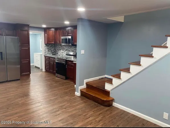 a kitchen with stainless steel appliances granite countertop a refrigerator and a wooden floors