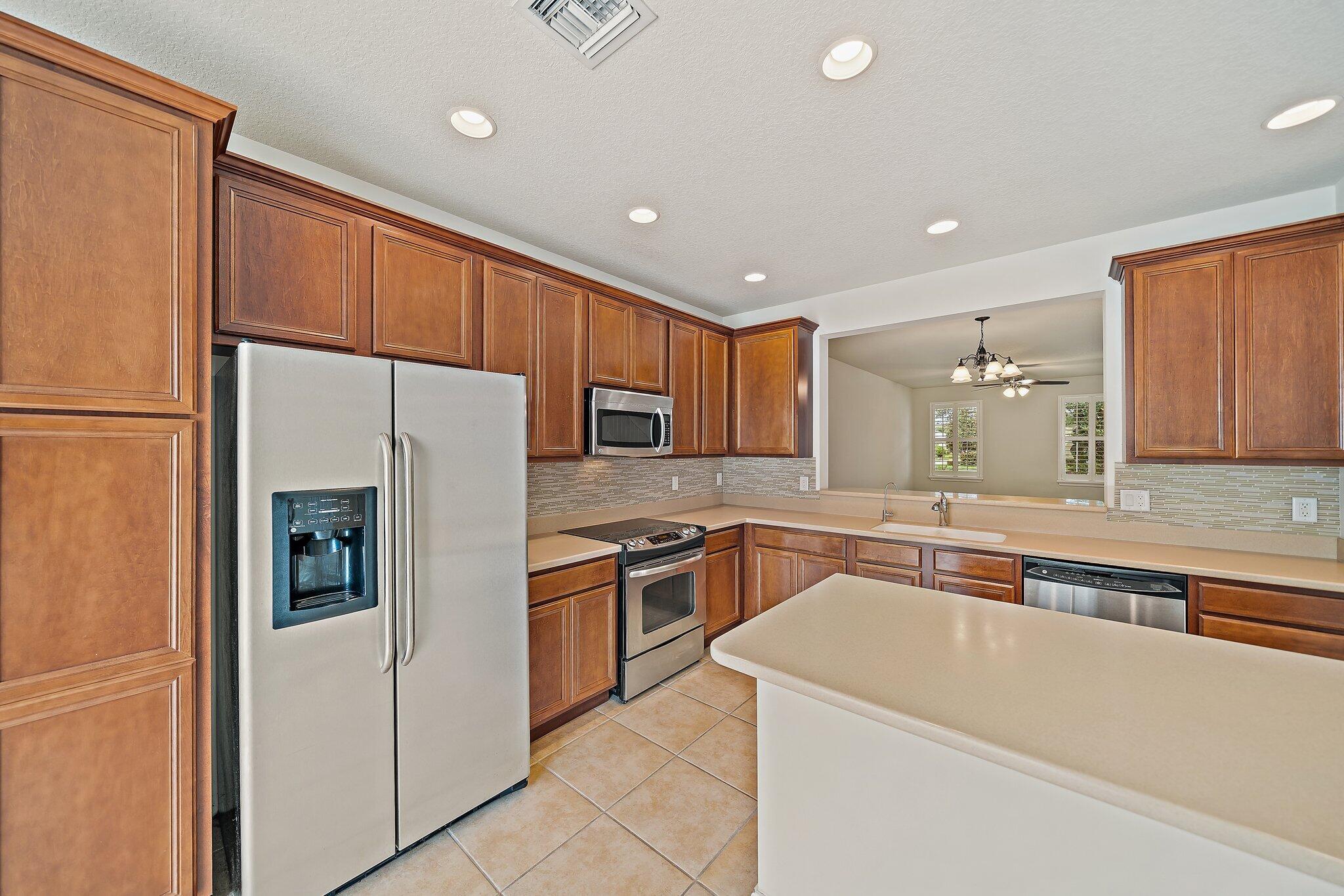 3253 Duncombe Drive Jupiter, FL 33458 - Photo 11 of 33 a kitchen with a refrigerator a sink and cabinets