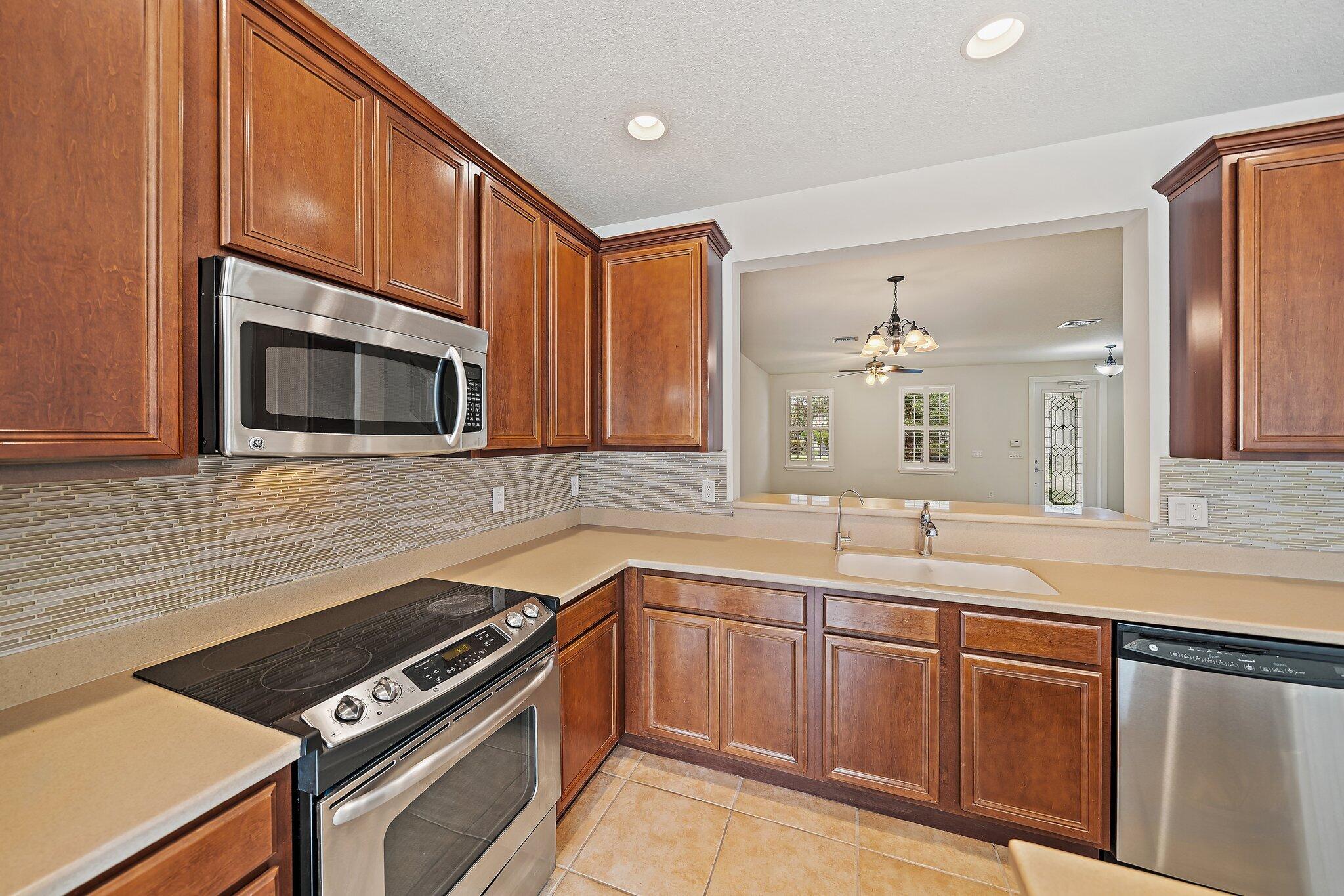 3253 Duncombe Drive Jupiter, FL 33458 - Photo 12 of 33 a kitchen with stainless steel appliances a sink stove and microwave