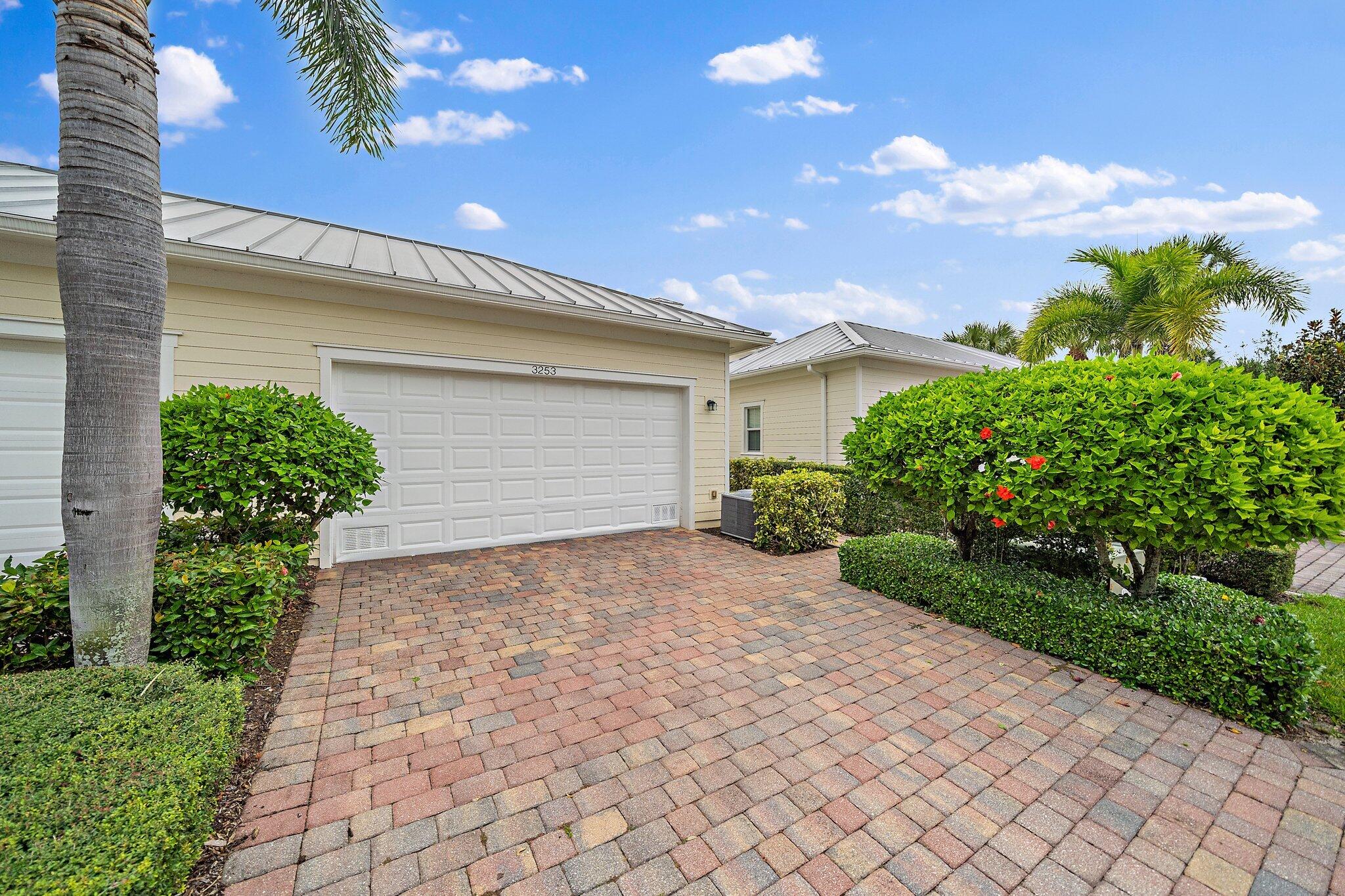 3253 Duncombe Drive Jupiter, FL 33458 - Photo 26 of 33 a front view of a house with a yard and a garage
