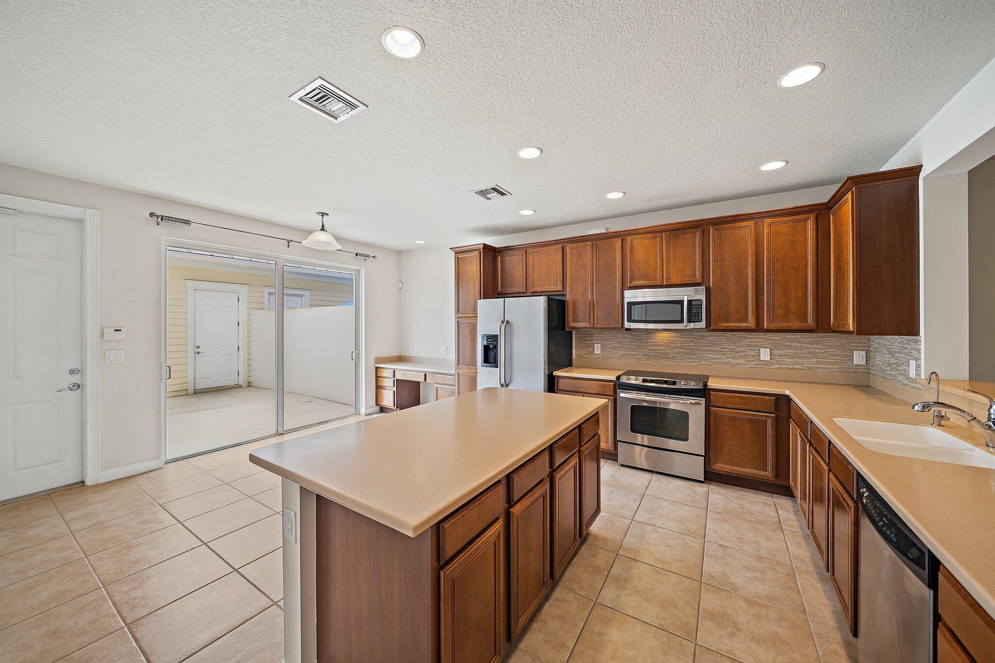 3253 Duncombe Drive Jupiter, FL 33458 - Photo 9 of 33 a kitchen with stainless steel appliances granite countertop a refrigerator a sink dishwasher a s stove top oven a sink and dishwasher