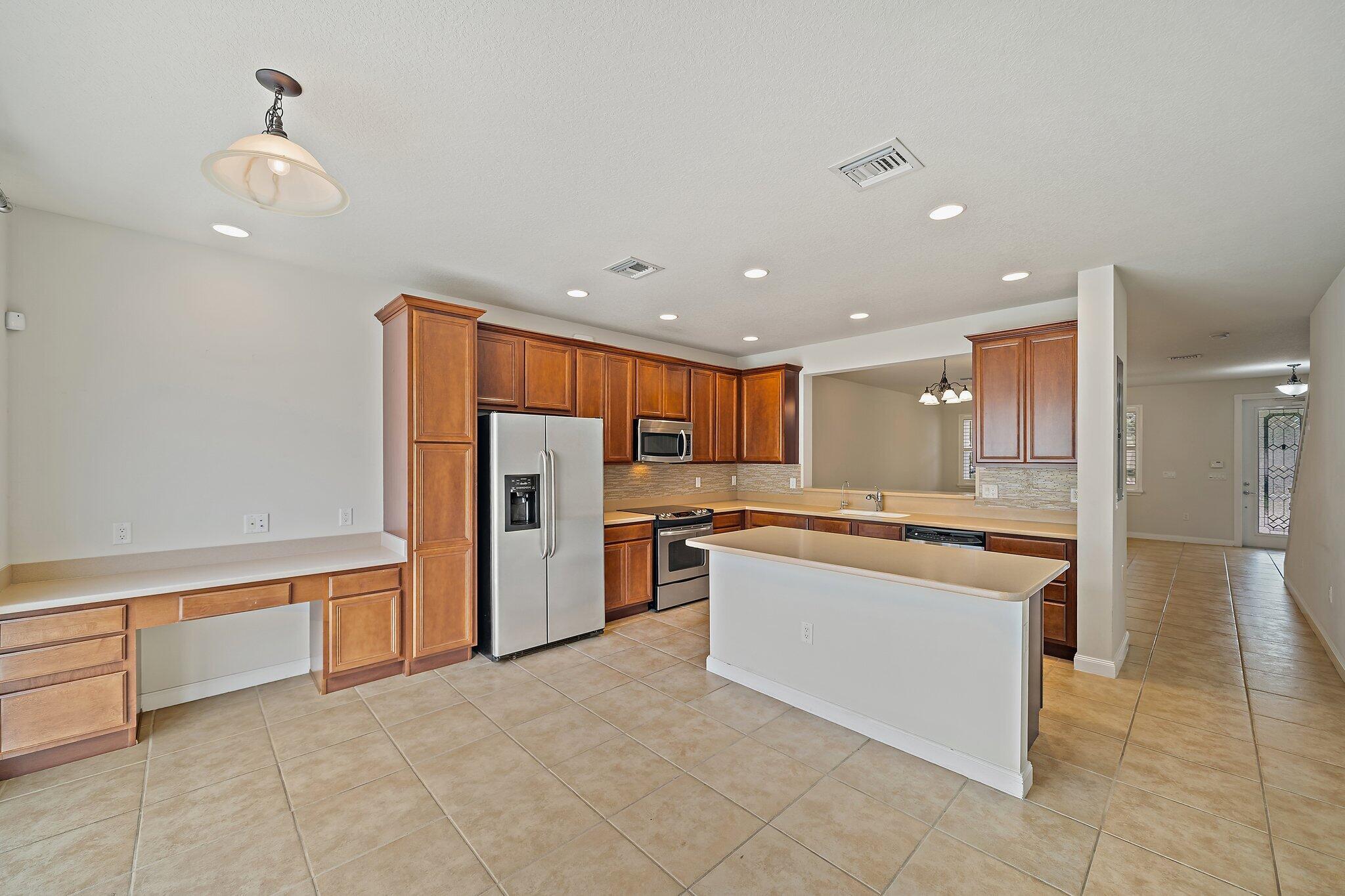 3253 Duncombe Drive Jupiter, FL 33458 - Photo 10 of 33 a large kitchen with stainless steel appliances granite countertop a refrigerator and a stove top oven