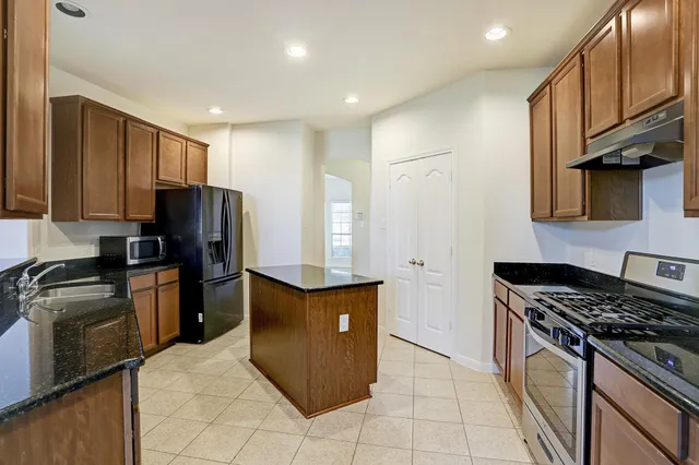 a kitchen with stainless steel appliances granite countertop a stove a refrigerator and a sink