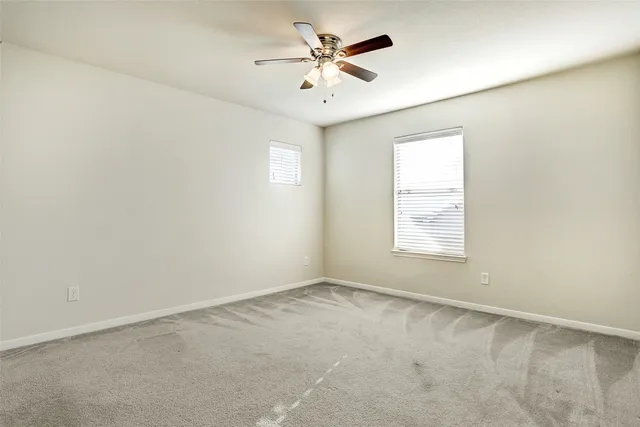 an empty room with windows and fan