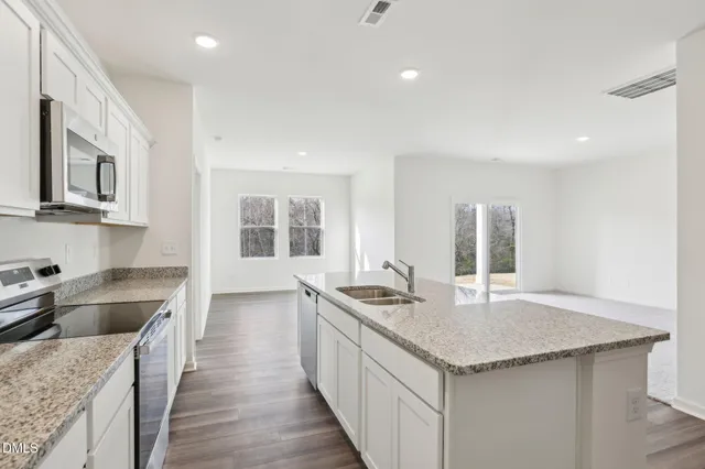 a kitchen with granite countertop stainless steel appliances a sink a stove and a center island