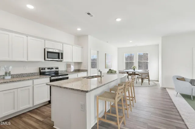 a large kitchen with granite countertop a stove a sink a dining table and chairs