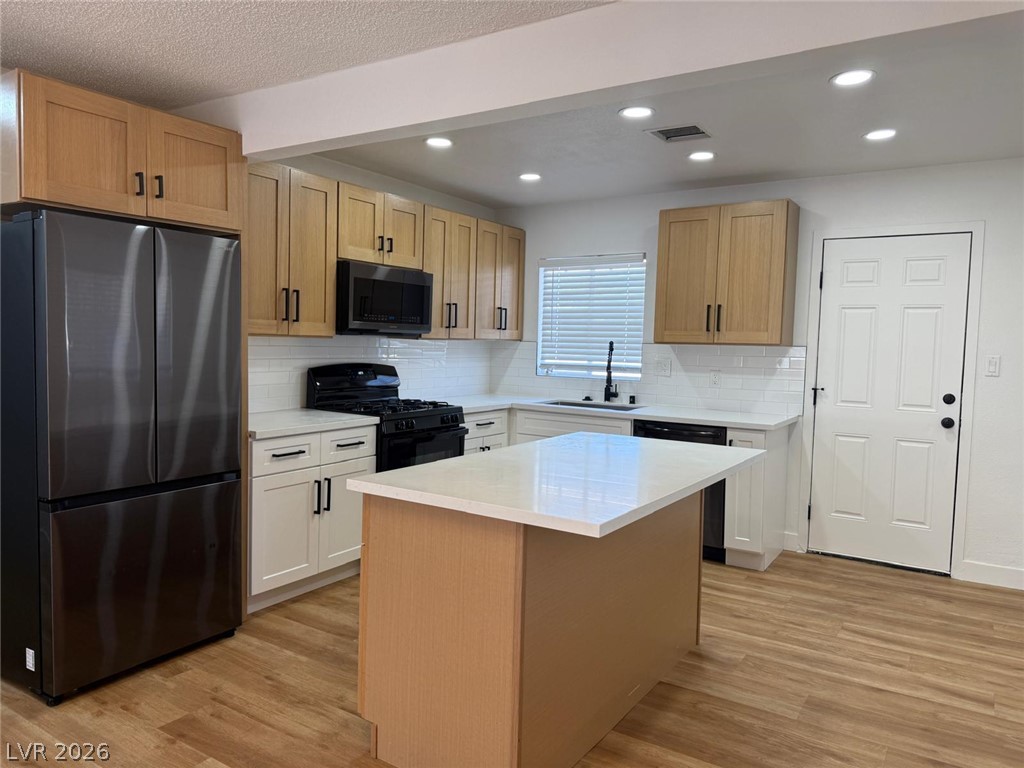 148 Fir Street Henderson, NV 89015 - Photo 3 of 12 Gleaming stone countertops and warm wood floors define this fully updated kitchen space.