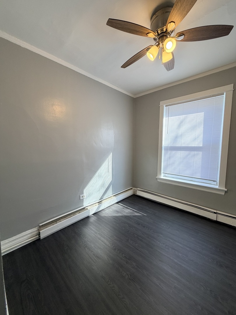 7700 South Green Street, Unit 1 Chicago, IL 60620 - Photo 6 of 11 an empty room with wooden floor fan and windows
