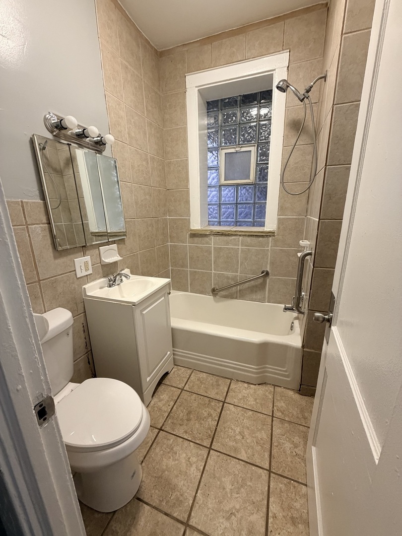 7700 South Green Street, Unit 1 Chicago, IL 60620 - Photo 9 of 11 a bathroom with a toilet a sink a mirror a bathtub and shower