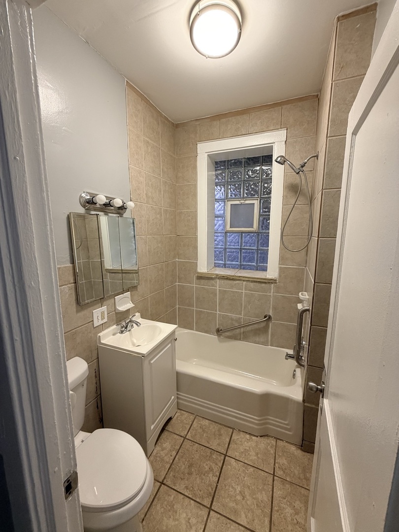 7700 South Green Street, Unit 1 Chicago, IL 60620 - Photo 10 of 11 a bathroom with a sink a toilet a mirror a vanity and bathtub