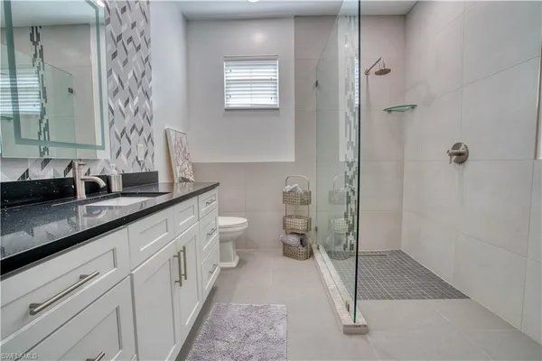 a spacious bathroom with a double vanity sink a toilet and a mirror