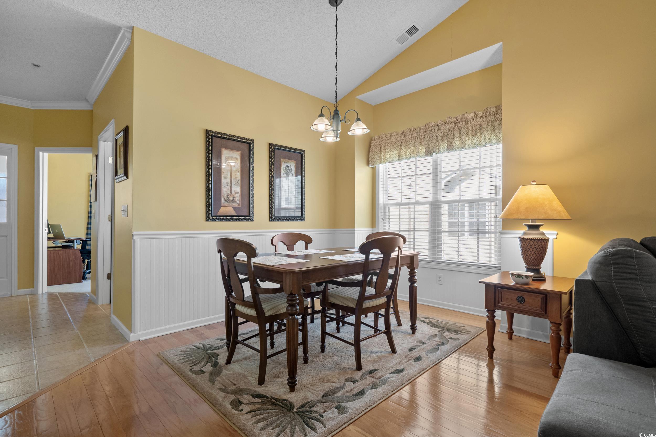 5852 Longwood Drive, Unit 301 Murrells Inlet, SC 29576 - Photo 13 of 35 Dining space with light wood-style flooring, lofted ceiling, a chandelier, and a wainscoted wall