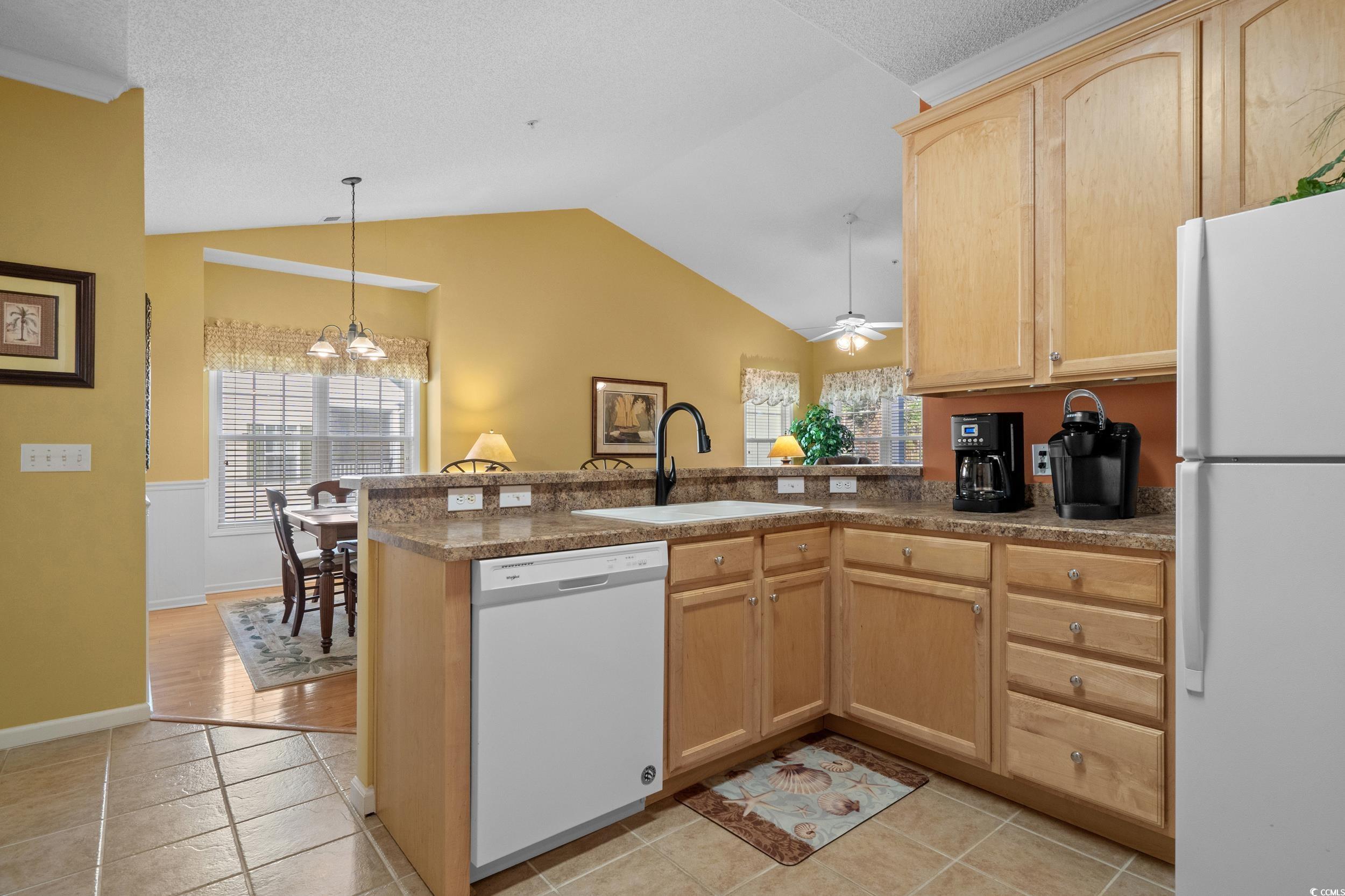 5852 Longwood Drive, Unit 301 Murrells Inlet, SC 29576 - Photo 16 of 35 Kitchen featuring light brown cabinetry, white appliances, lofted ceiling, pendant lighting, and a peninsula