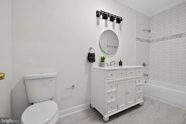 a bathroom with a toilet a sink a mirror and a bathtub